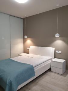 Un dormitorio con una gran cama blanca con una manta azul. en Best Apartment Shevchenka 80, en Leópolis