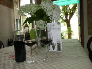 two glasses of wine on a table with a bottle of wine at Cascina Tornara, ritorno alle origini monferrine in Ozzano Monferrato