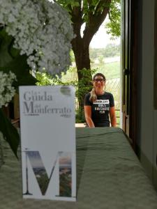 een vrouw aan een tafel naast een bord bij Cascina Tornara, ritorno alle origini monferrine in Ozzano Monferrato
