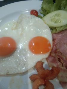 two fried eggs and bacon on a plate with broccoli at Cessna Park Resort and Hotel in Ban Hua Na