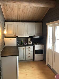 a kitchen with white appliances and a wooden ceiling at Skysstasjonen Cottages in Røldal