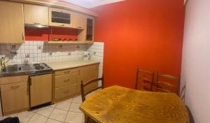 a kitchen with an orange wall and a table and a sink at Domek wiejski in Dwernik