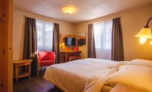 a hotel room with a bed and a red chair at Guesthouse by the rex in Zermatt