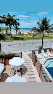 een patio met tafels en stoelen en een zwembad bij Pousada La Naila in Bertioga