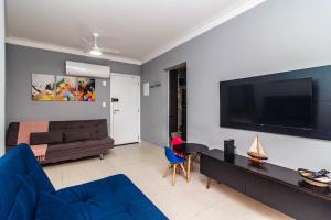 un salon avec un canapé et une télévision à écran plat dans l'établissement Piemax Praia Grande - 100m PRAIA do BOQUEIRÃO e CENTRO - Vista MAR - Varanda GOURMET com CHURRASQUEIRA privativa - AR CONDICIONADO em todos os ambientes - Wi-Fi 600 Mbps - HOME OFFICE- Vaga de Garagem - Acomoda até 6 pessoas, à Praia Grande