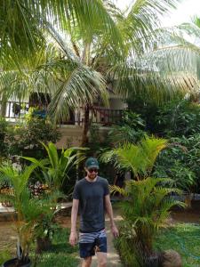 a man standing in front of a palm tree at Little Sunshine Guest House & Restaurant in Tangalle