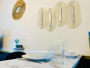 einen Tisch mit Tellern und Gläsern und ein Schild an der Wand in der Unterkunft Homard & Fox, Le Féart, Studio avec coin terrasse & barbecue in Dinard