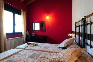 Dormitorio rojo con cama y espejo en El Valle de la Mantequilla, en Aldehuela del Rincón