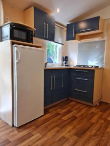 uma cozinha com armários azuis e um frigorífico branco em MOBIL HOME familiale EN ALSACE11 KM DES GRANDS PARCS em Boofzheim