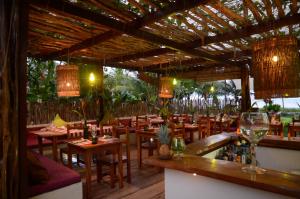 un restaurante con mesas de madera, sillas y lámparas de araña en Praiagogi Boutique Pousada, en Maragogi