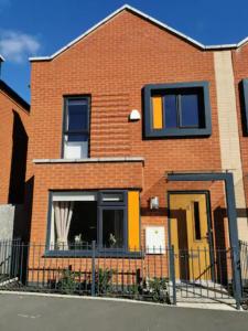 a red brick house with a yellow door at Entire 3 bedroom house Manchester free parking in Manchester