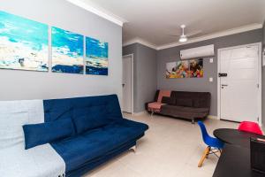 sala de estar con sofá azul y cama en Piemax Praia Grande - 100m PRAIA do BOQUEIRÃO e CENTRO - Vista MAR - Varanda GOURMET com CHURRASQUEIRA privativa - AR CONDICIONADO em todos os ambientes - Wi-Fi 250 Mbps - HOME OFFICE- Vaga de Garagem - Acomoda até 6 pessoas en Praia Grande