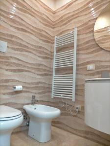 Un baño con inodoro, lavabo y espejo. en SCENU', en Martina Franca
