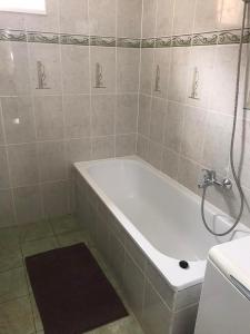 a white bath tub in a bathroom with a shower at Gemini apartman in Hajdúszoboszló