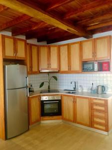a kitchen with wooden cabinets and a stainless steel refrigerator at Alo Baía São Lourenço in Santa Bárbara