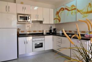 eine Küche mit weißen Schränken und einem weißen Kühlschrank in der Unterkunft Casa de los Limones by Costadelsolholiday FAMILY VILLA NEAR PUERTO MARINA in Benalmádena