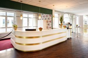 a lobby with a reception counter with gold stripes at Cascada Central Hotel Rheine in Rheine