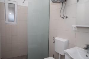 
a white toilet sitting next to a shower in a bathroom at Apartment Kravica in Ljubuški

