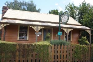 un pequeño edificio con una valla delante en Westbury Gingerbread Cottages, en Westbury