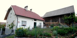 ein weißes Haus mit einem roten Dach und einem Garten in der Unterkunft Ostir Holiday Home in Cerknica