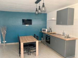 a kitchen with a wooden table and a blue wall at Gites des Lavandières in Cour-Cheverny