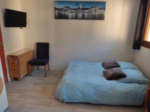 a bedroom with a bed and a chair and a television at Le Guisanel in Briançon