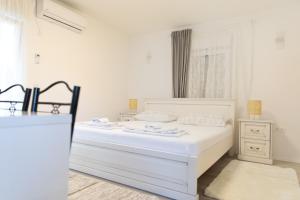 een witte slaapkamer met een wit bed en een raam bij Apartment Kravica in Ljubuški