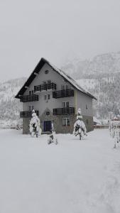 a large building in the snow with snow covered trees at Guesthouse Drinos Valbone in Valbonë