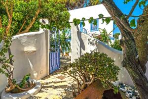 una casa blanca con una puerta azul y árboles en Pleiades Alinda Bay Leros, en Alinda