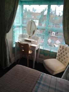 a bedroom with a dressing table and a mirror and a window at Schofield Guest House in Bridlington