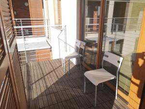 a balcony with two white chairs and a table at Apartament Marzenie 10 - Opole in Opole