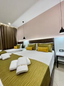 two beds in a hotel room with yellow and white pillows at Relax Apts Saranda in Sarandë