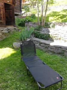 a black bench sitting in the grass in a yard at Chalet 3 chambres à Sarreyer, proche Verbier in Sarreyer