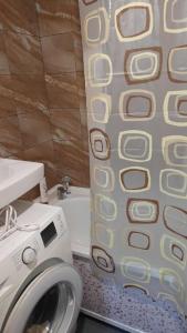 a shower curtain in a bathroom with a washing machine at Уютные апартаменты в историческом центре in Aktobe