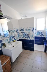 ein Bad mit einem Waschbecken und blauen und weißen Fliesen in der Unterkunft Gîte de Catherine in Saint-Didier