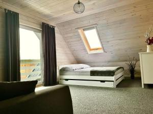 a bedroom with a bed and a window and a couch at Białe Domki Lubiatowo in Lubiatowo