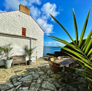 a patio with a table and chairs and the ocean at Unique Retreat - 2 bedroom cliff top cottage with large terrace in Portloe