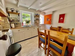 a kitchen with a wooden table and a dining room at Unique Retreat - 2 bedroom cliff top cottage with large terrace in Portloe