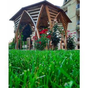 einen hölzernen Pavillon mit Blumen im Gras in der Unterkunft Gabala Yeddi Gozel Hotel in Qəbələ
