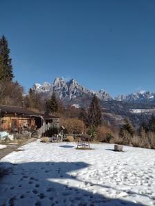 a snow covered yard with mountains in the background at Baita Zeni Tirolerhof - Adult friendly in Fiera di Primiero