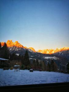 a snow covered field with mountains in the background at Baita Zeni Tirolerhof - Adult friendly in Fiera di Primiero
