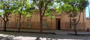 un antiguo edificio con árboles delante de él en La Casona en Godoy Cruz