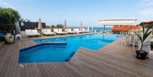 a large swimming pool with chairs and a deck at Anny Residences & Suites in Skala Kallirakhis