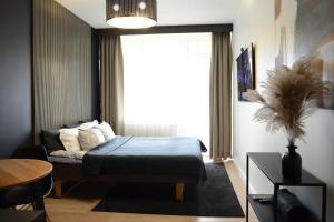 um quarto com uma cama e uma grande janela em Palanga-Apartamentai em Palanga