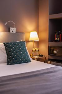 Cama con almohada y lámpara en una habitación en Hôtel Churchill Bordeaux Centre, en Burdeos