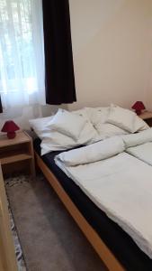 a bed with white sheets and pillows next to a window at Borostyán Vendégház in Tiszaug