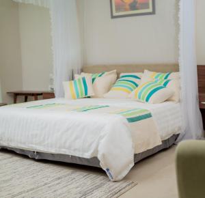 Bett mit weißer Bettwäsche und Kissen in einem Zimmer in der Unterkunft Lalibela Boutique Hotel in Lilongwe