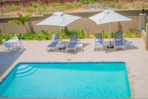 a swimming pool with chairs and white umbrellas at Lalibela Boutique Hotel in Lilongwe