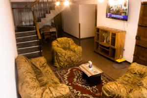 Una sala de estar con un sofá y sillas y un televisor. en Casa Libertad, en Cusco