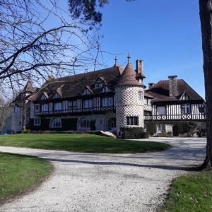 une grande maison avec une tourelle dans une allée dans l'établissement Chambres d'Hôtes Manoir de Beaumarchais, à Les Chapelles-Bourbon